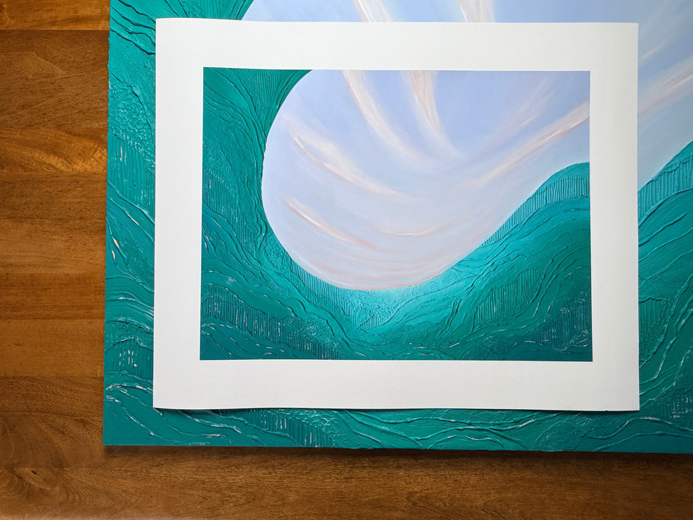 The Noon print lying flat on a wood table, showing the full cotton rag sheet with its wide white border around the image
