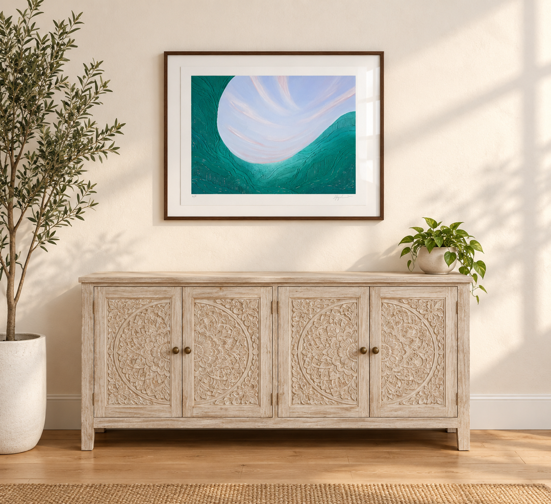 Noon framed and hung above a light wood sideboard with an olive tree, showing the scale of the print in a room